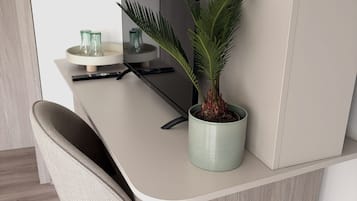 A modern, minimalist office desk with a potted plant, a remote control, and a glass container.