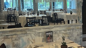 Interior de restaurante con techo de madera rústica, ventanas amplias y mesas dispuestas para comer.