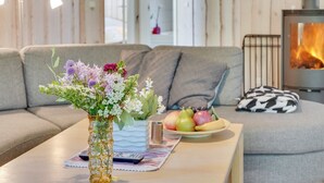 A cozy living room with a sofa, a coffee table with a vase of flowers, a fruit bowl, and a fireplace. - "Elita" - 1.7km from the sea by Interhome (Hals)