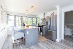 Una cocina moderna con una isla grande, electrodomésticos de acero inoxidable y vistas al exterior.