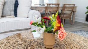 Ein Wohnzimmer mit rundem Couchtisch, einem weißen Sofa und einem Essbereich mit Holzsesseln.
