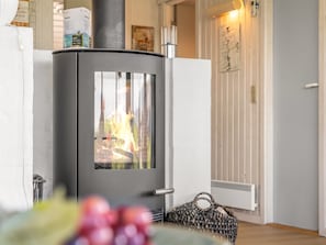 A modern room with a wood-burning stove, a radiator, and a woven basket.