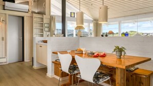 Eine moderne Küche mit Holztisch, weißen Stühlen und Blick ins Freie.