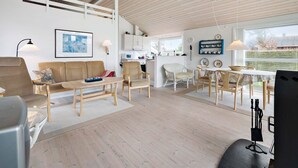 Un vaste espace de vie doté d’un haut plafond, d’un canapé, d’une table à manger et d’un coin cuisine visible grâce à un espace ouvert.