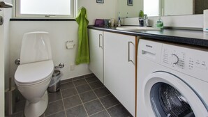 Une petite salle de bain comprenant des toilettes, un lavabo et un lave-linge.