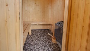 Un sauna en bois, avec un banc, un sol carrelé en pierre et un appareil de chauffage pour sauna.