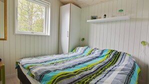 Une chambre à coucher comprenant un lit, une fenêtre, une armoire et une étagère avec des objets.