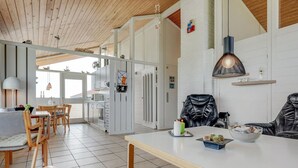 Una cocina moderna con armarios blancos, un comedor con sillas de madera y un ventanal que proporciona luz natural.