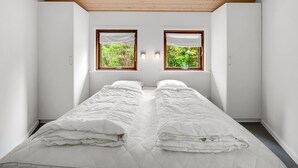 A bedroom with two beds, a sloped ceiling, and two windows with curtains. - "Reiner" - 300m to the fjord by Interhome (Skjern)
