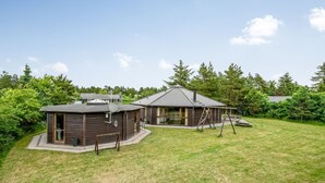 A two-story wooden house with a fenced yard, a swing set, and a satellite dish. - "Reiner" - 300m to the fjord by Interhome (Skjern)
