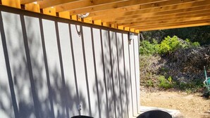 Un patio techado con una mesa redonda y cuatro sillas de mimbre.