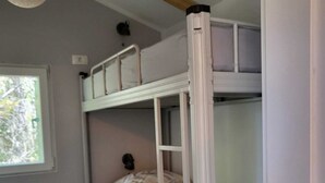 Dormitorio con literas, ventana, vigas de madera y lámpara.