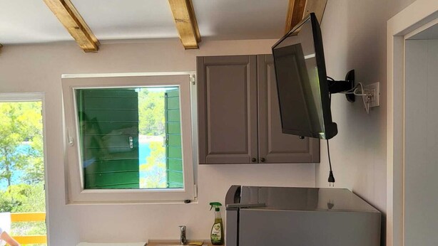 A compact kitchen with a built-in oven, a sink, and a refrigerator. There is a window with a view of greenery outside. - New vacation home with 2 terraces, right by the sea - a dream surrounded by forest (Murter)