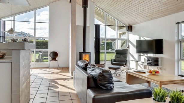 A modern living room with a fireplace, a sofa, a TV, and a dining area.