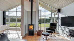 A modern living room with a fireplace, large windows, a TV, and a comfortable seating area.