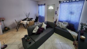 Una sala de estar con un sofá, una mesa de comedor y un ventilador.