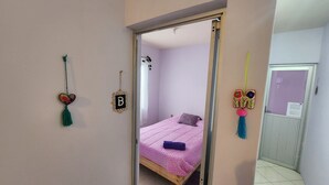 Un dormitorio con cama, una puerta y una pared decorada.
