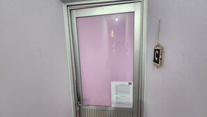 Una puerta con interior rosa, un lector de tarjetas de seguridad y un letrero con texto.