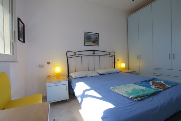 A bedroom with a bed, nightstands, a wardrobe, and a window.