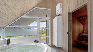 Uma área de spa com hidromassagem, paredes de madeira e uma grande janela.