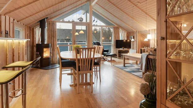 A cozy cabin interior with a wooden dining area, a fireplace, a television, and a glass cabinet with wine glasses. - "Thit" - 1.2km to the fjord by Interhome (Hemmet)
