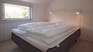 Ein Schlafzimmer mit einem Bett, einem Fenster und zwei Wandleuchten.