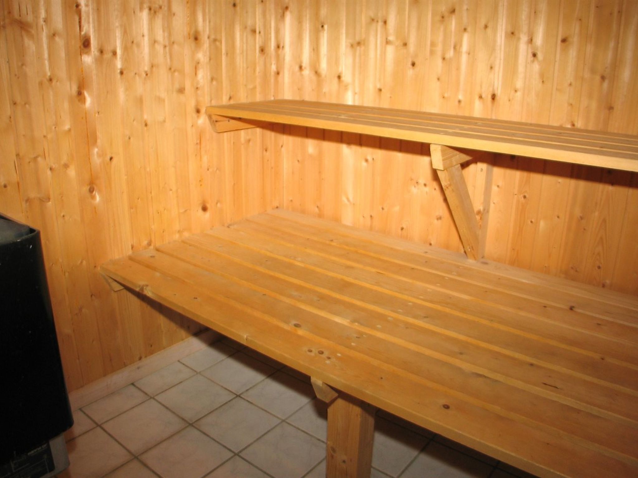 A wooden sauna with a bench and a slanted shelf.
