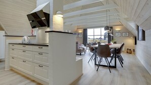 A modern kitchen with white cabinetry, a central island, and a dining area with a large window offering a view. - "Ege" - 200m from the sea by Interhome (Blåvand)