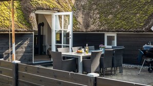 An outdoor dining area with a table and chairs, a grill, and a thatched roof structure. - "Ege" - 200m from the sea by Interhome (Blåvand)