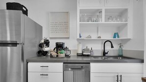 Eine moderne Küche mit Edelstahlgeräten, weißen Schränken und einer Kaffeemaschine auf der Arbeitsplatte.