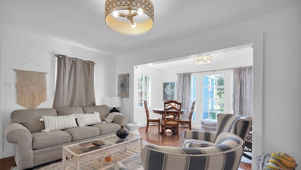 Ein Wohnzimmer mit einer Couch, Sesseln, einem Couchtisch und einem Essbereich mit Tisch und Stühlen.