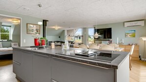 Een moderne keuken met een groot eiland, inbouwapparatuur en een eethoek met uitzicht.