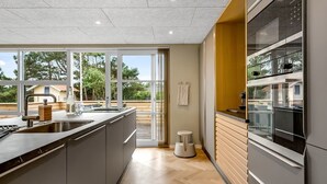 Een moderne keuken met een groot kookeiland, een inbouwoven en uitzicht op de omgeving.