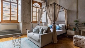 Un dormitorio con una cama con dosel, un sofá y una mesita de noche.