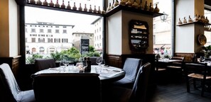 Un restaurant avec des tables dressées, un tableau affichant le menu et une vue sur la rue.