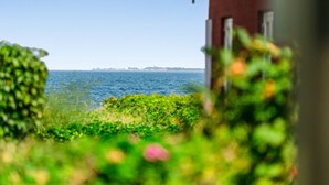 Blick auf das Meer, mit einem roten Gebäude im Vordergrund.