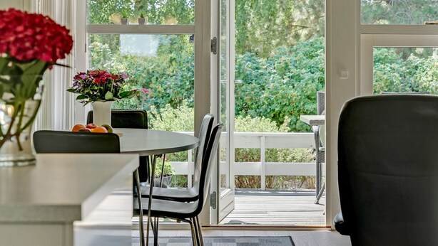 Ein Wintergarten mit Esstisch, Stühlen und einer Blumenvase.