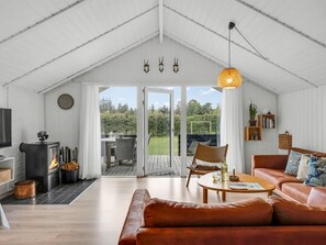 A cozy living room with a fireplace, a sofa, a coffee table, and a dining area with chairs. - "Ilsi" - 1.5km from the sea by Interhome (Blåvand)