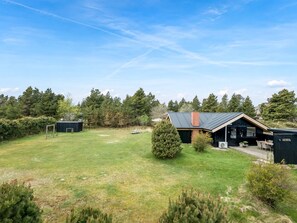 Un espace extérieur verdoyant avec un bâtiment doté d’un toit en pente et d’une cheminée.