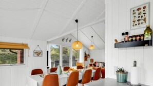 A modern kitchen with a dining area, white cabinetry, and a variety of kitchen items on shelves. - "Ilsi" - 1.5km from the sea by Interhome (Blåvand)