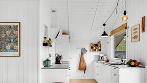 A modern kitchen with white cabinetry, a dining area with a table and chairs, and a hanging light fixture. - "Ilsi" - 1.5km from the sea by Interhome (Blåvand)