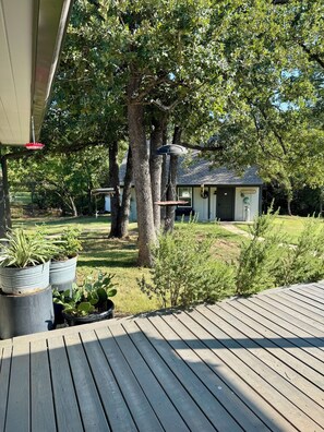A wooden deck with potted plants, a house with a 'WELCOME' sign, and a clear sky.