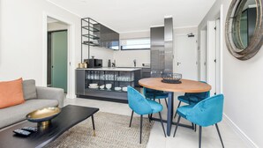 A modern living room with a sofa, a coffee table, and a dining area with chairs and a table. - The Emerald 42 (Sandton)