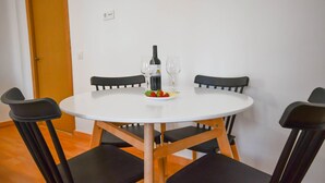 A round white table with four black chairs, a bottle of wine, two wine glasses, and a plate with strawberries. - APARTAMENTO TETUAN "CASTELLANA" (Madrid)