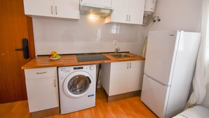 A compact kitchen with white cabinets, a washing machine, a sink, and a refrigerator. - APARTAMENTO TETUAN "CASTELLANA" (Madrid)