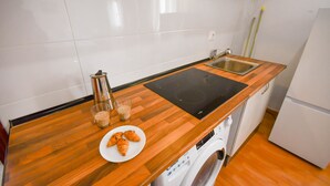A kitchen with a wooden countertop, a sink, a coffee maker, and a washing machine. - APARTAMENTO TETUAN "CASTELLANA" (Madrid)