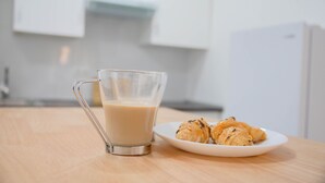 Kirkas lasimuki, joka on täytetty juomalla, valkoinen lautanen, jossa on croissantteja, ja puinen pöytä keittiössä.