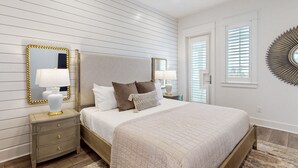 Une chambre à coucher avec un grand lit, deux tables de chevet, un miroir et un élément décoratif fixé au mur.
