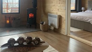 Una cabaña de madera acogedora con chimenea, cama y una mesa con tazas.