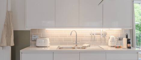 A modern kitchen with white cabinets, a stainless steel sink, and a built-in toaster.